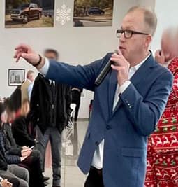 David Aahl in a blue blazer calling an auction in front of a seated audience