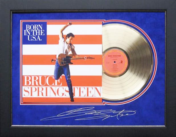 Framed gold record displayed beside the Bruce Springsteen Born in the U.S.A. album cover with a laser-reproduced signature, offered as a charity auction lot