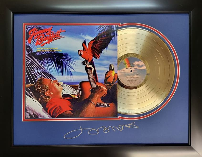 Framed gold record displayed beside the Jimmy Buffett album cover with a laser-reproduced signature, offered as a charity auction lot