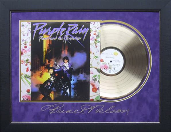 Framed gold record displayed beside the Prince Purple Rain album cover with a laser-reproduced signature, offered as a charity auction lot