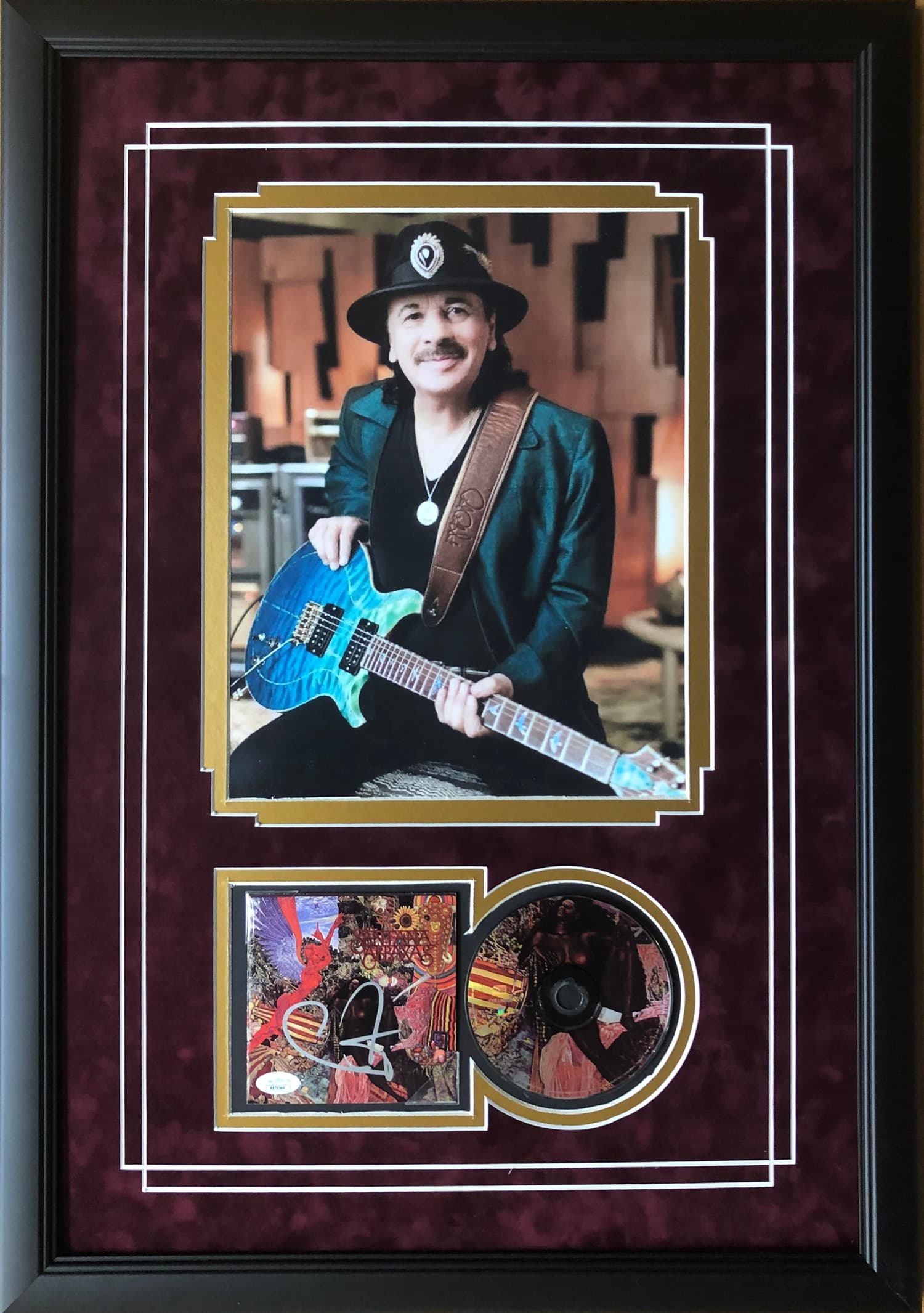 Framed Carlos Santana commemorative display presented with a hand-signed CD, offered as a charity auction lot