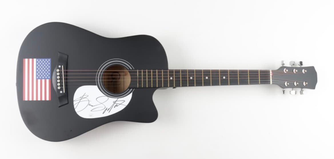 Black acoustic guitar hand-signed by Bruce Springsteen with American flag artwork on the body, a charity auction lot