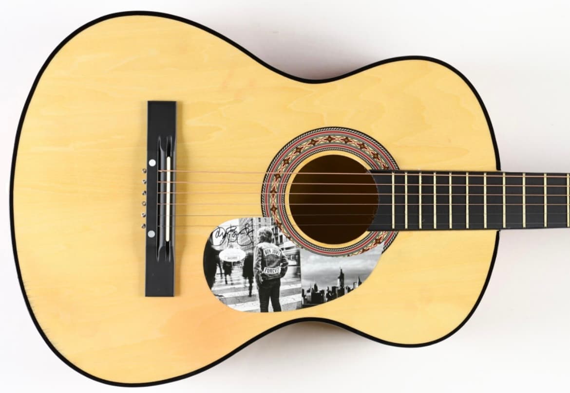 Natural finish acoustic guitar hand-signed by Jon Bon Jovi with a band photo inlay on the body, a charity auction lot